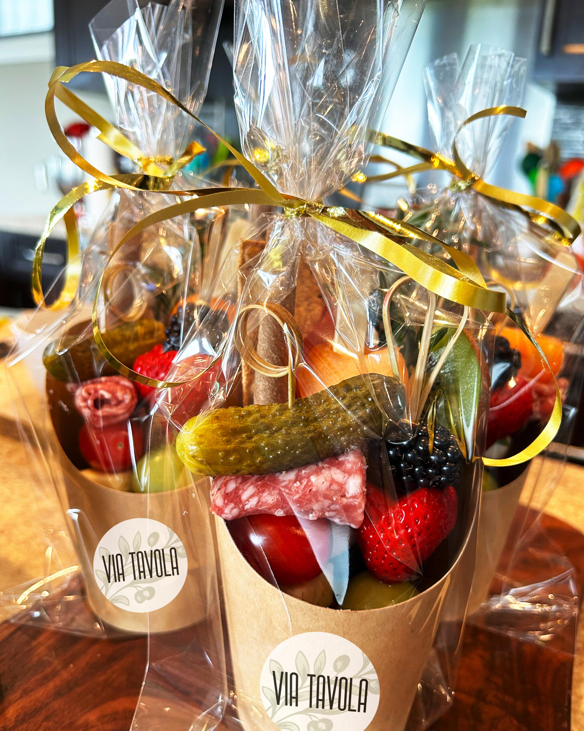 Beautiful paper cups filled with charcuterie items in festive wrapping.